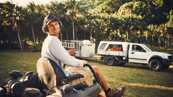 Smiling person sitting on a zero-turn ride-on mower