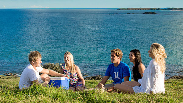 Group of friends having a picnic on the headland overlooking the ocean